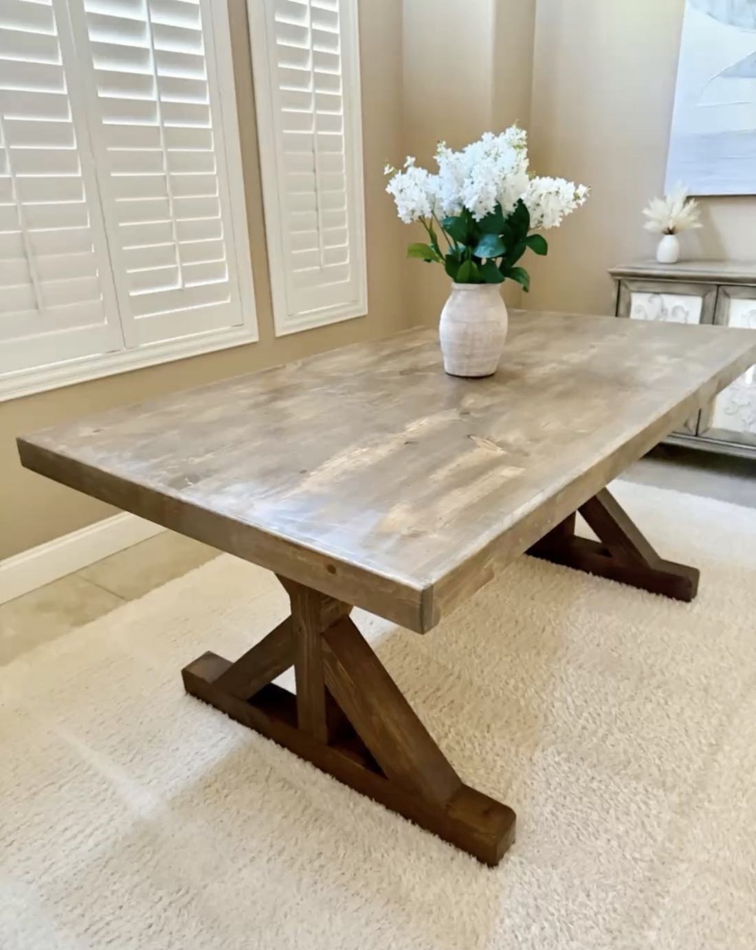 Weathered gray farmhouse table set with a vase of white flowers