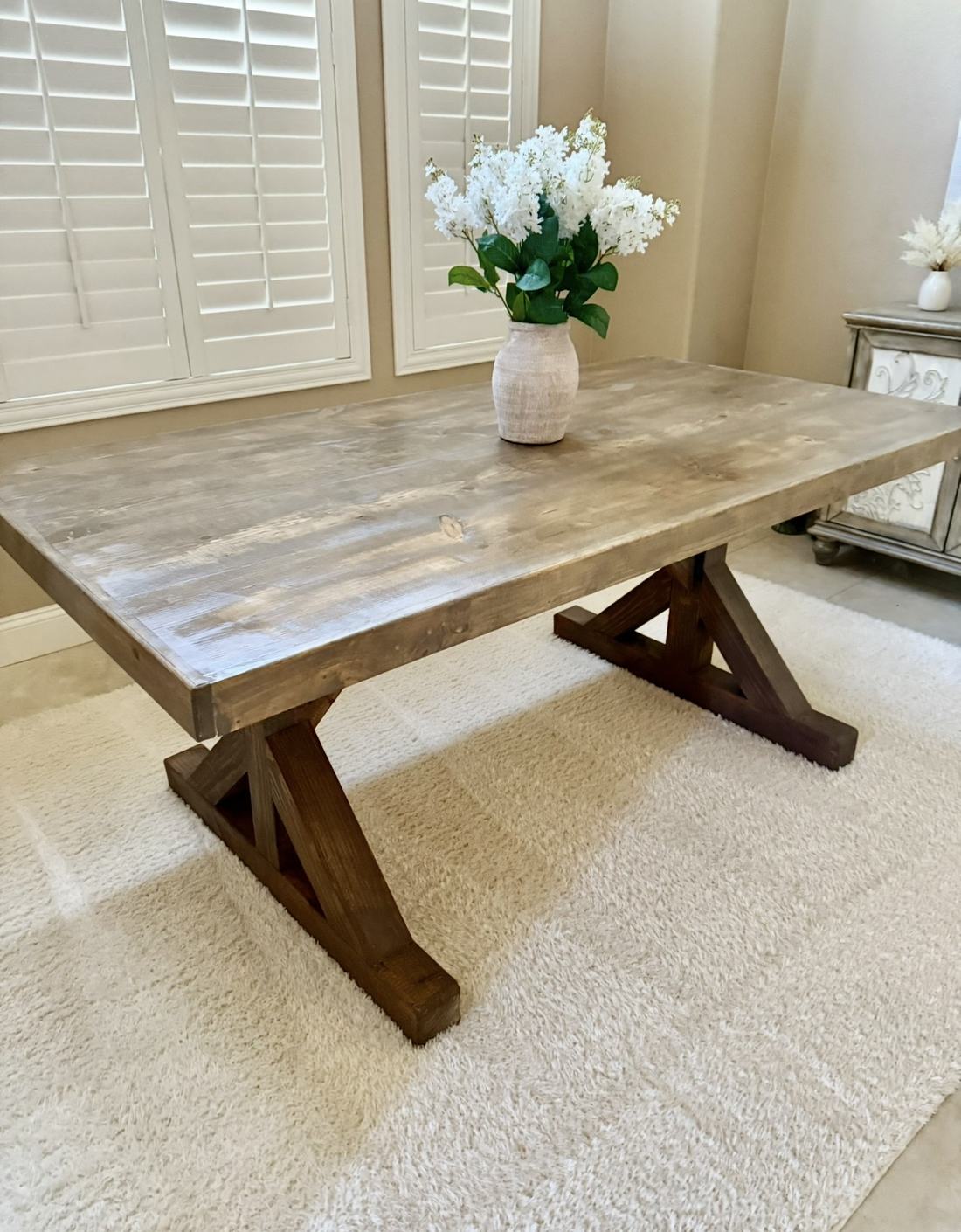Farmhouse table in a weathered gray finish with a dark stained trestle base