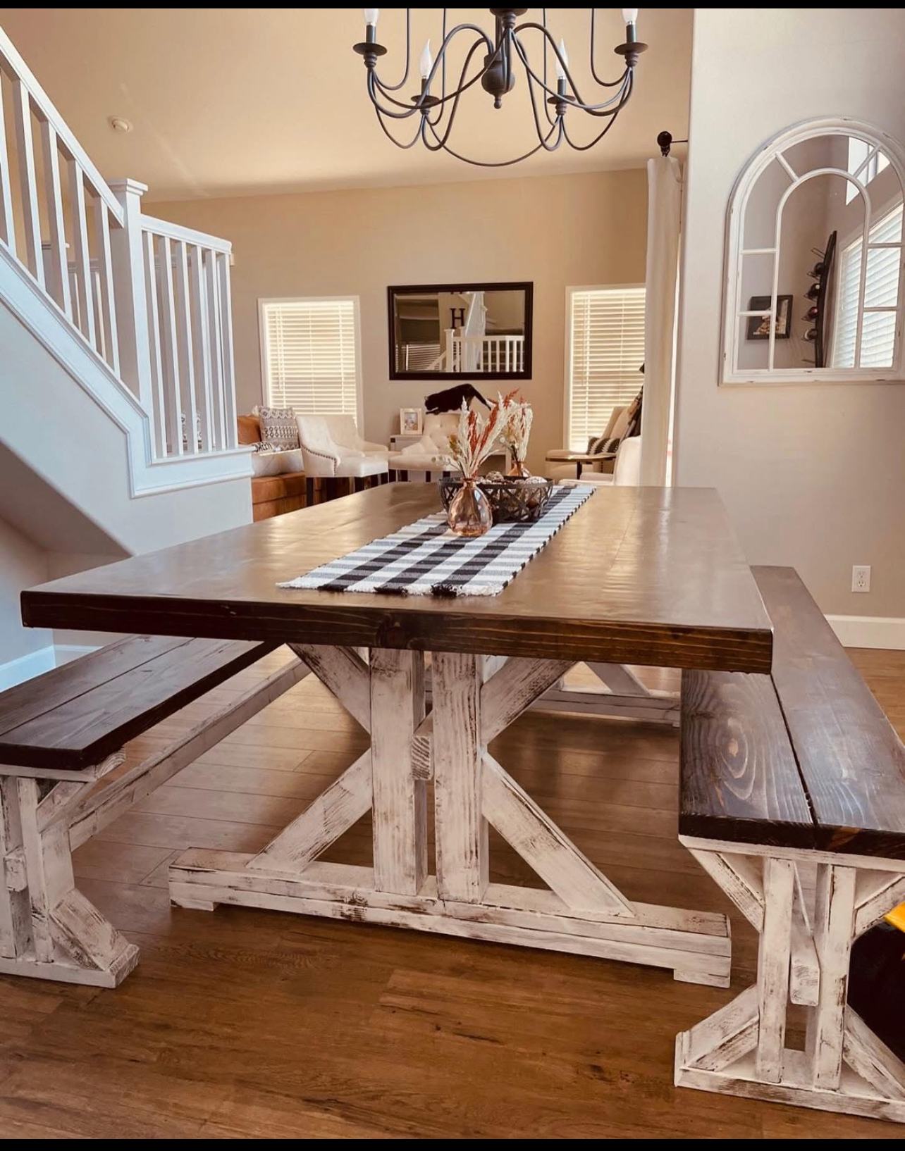 Handmade farmhouse dining table with dark walnut top and distressed white trestle base, with two matching benches
